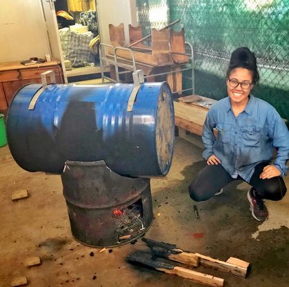 IdentityX Ambassador Trang Luu poses with a horizontal cookstove in South Africa